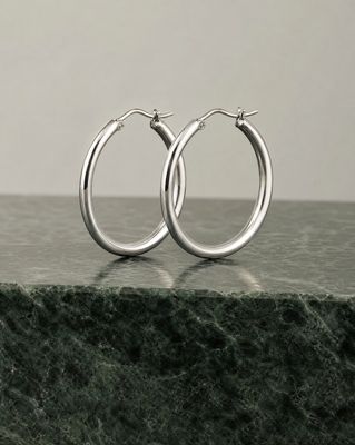 a pair of silver hoop earrings on a marble surface
