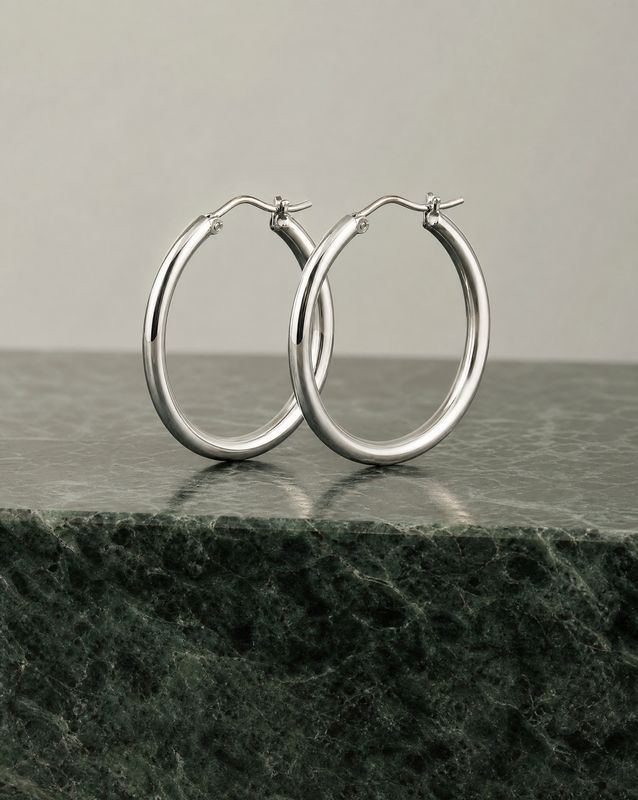 a pair of silver hoop earrings on a marble surface