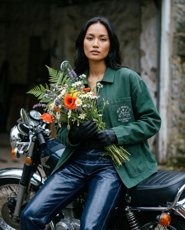 a woman sitting on a motorcycle holding a bunch of flowers
