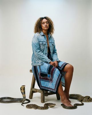 a woman sitting on a chair next to a snake