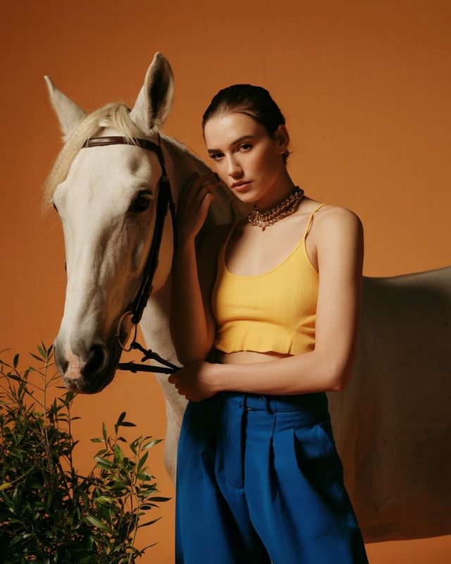 a woman standing next to a white horse