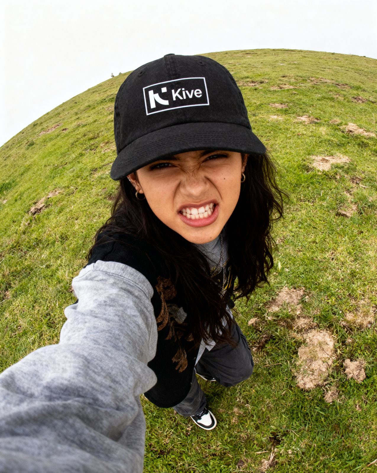 a woman in a black hat is standing in the grass