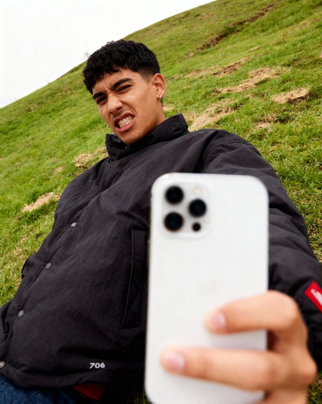 a man sitting in the grass holding a cell phone
