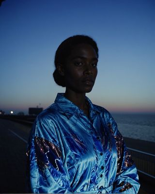 a woman standing on the side of a road next to the ocean