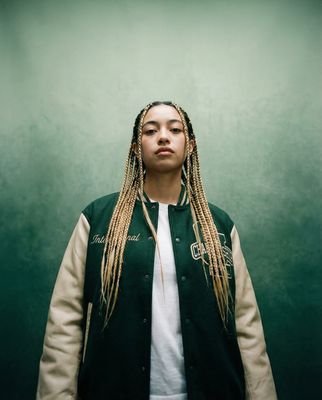 a woman with dreadlocks standing in front of a green wall