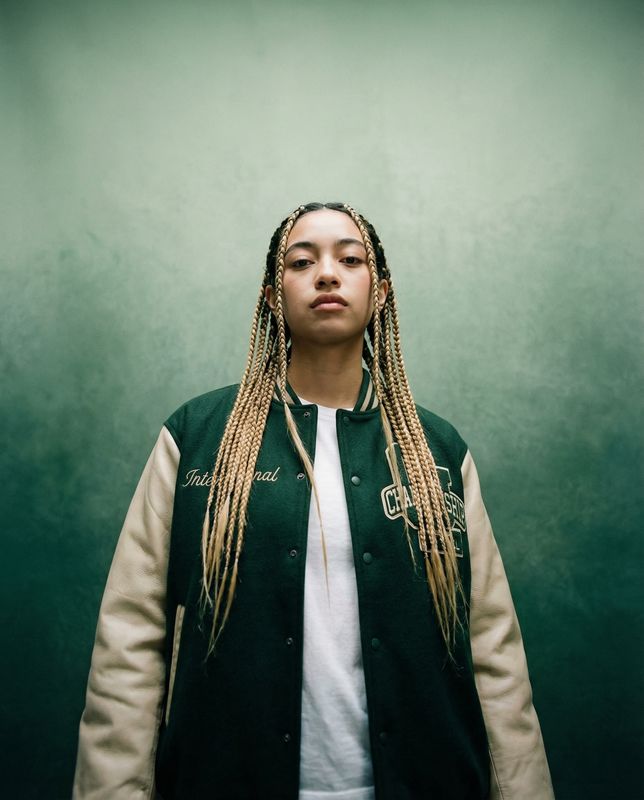 a woman with dreadlocks standing in front of a green wall