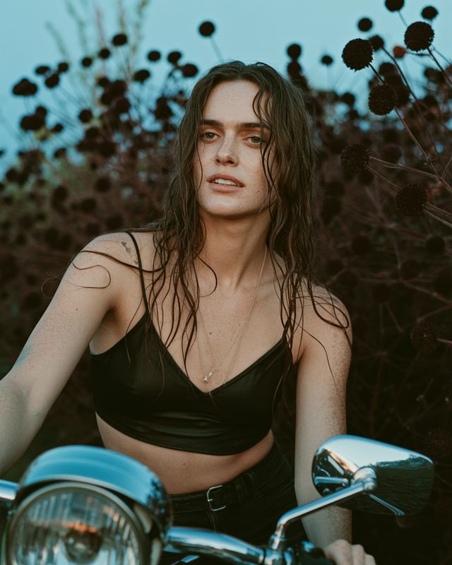 a woman with wet hair sitting on a motorcycle