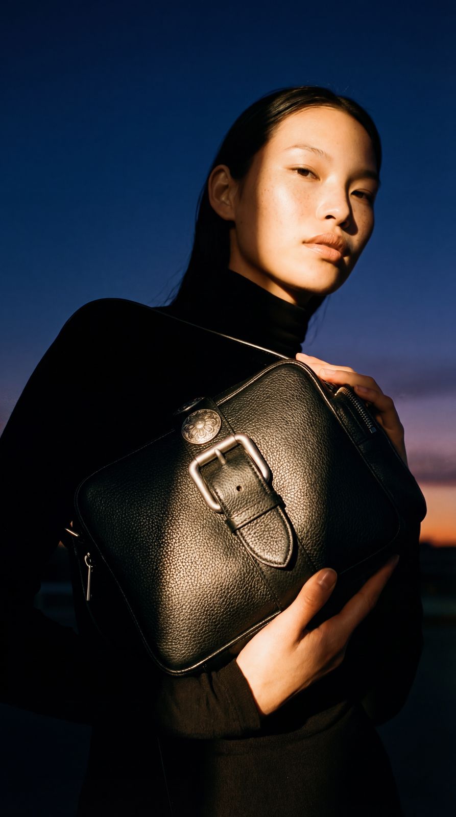 a woman holding a black purse in her hands