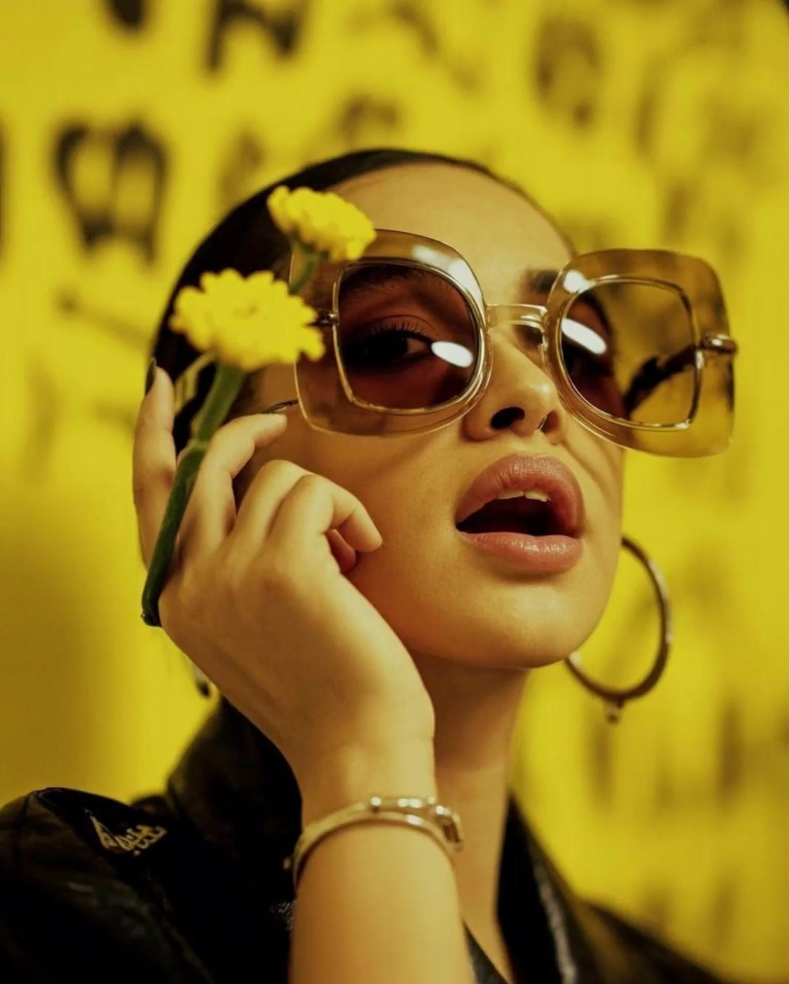 a woman wearing sunglasses and holding a flower