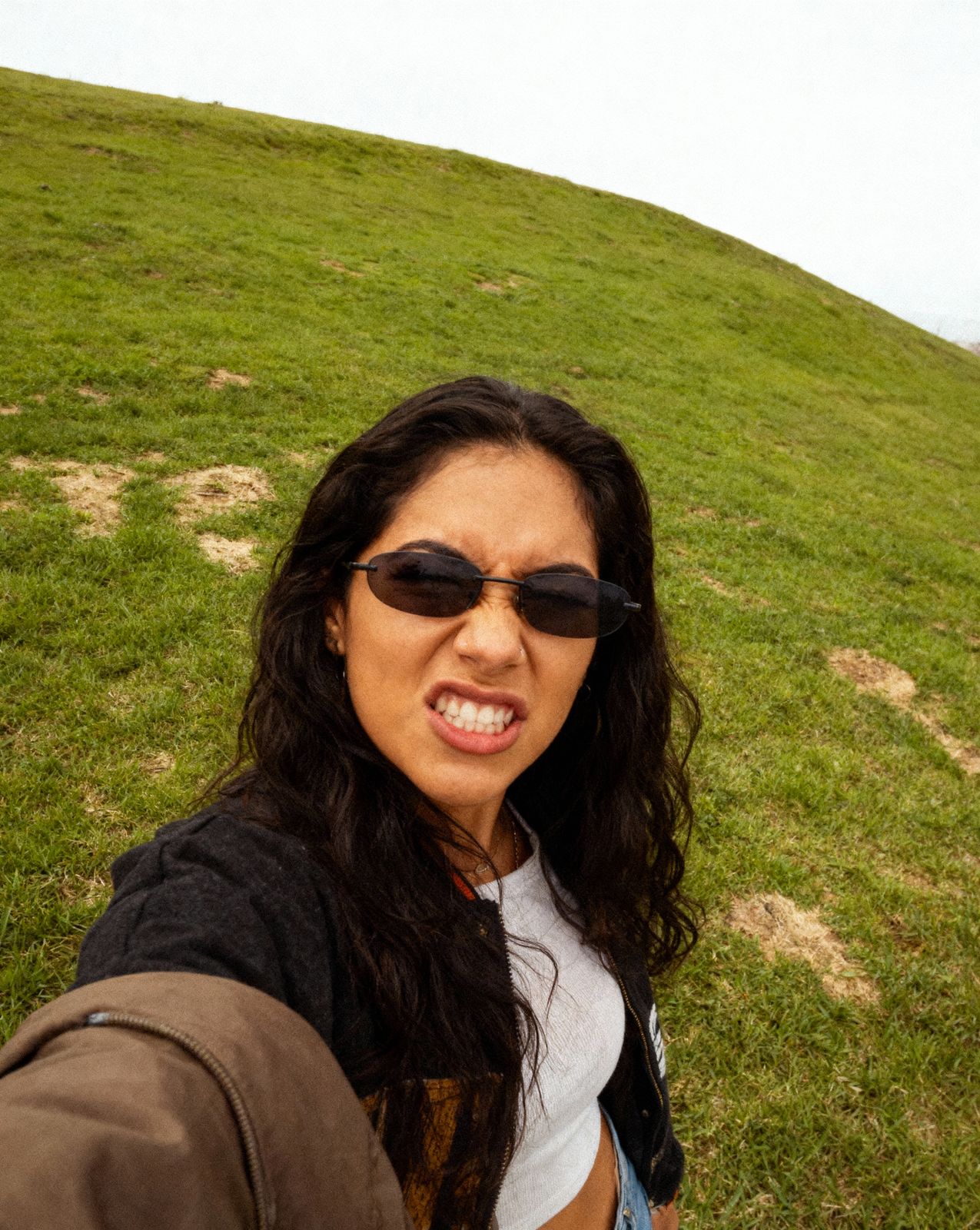 a woman wearing sunglasses standing on top of a lush green hillside