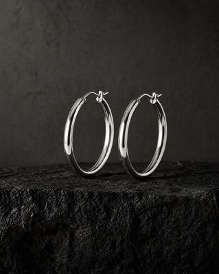 a pair of silver hoop earrings sitting on top of a rock