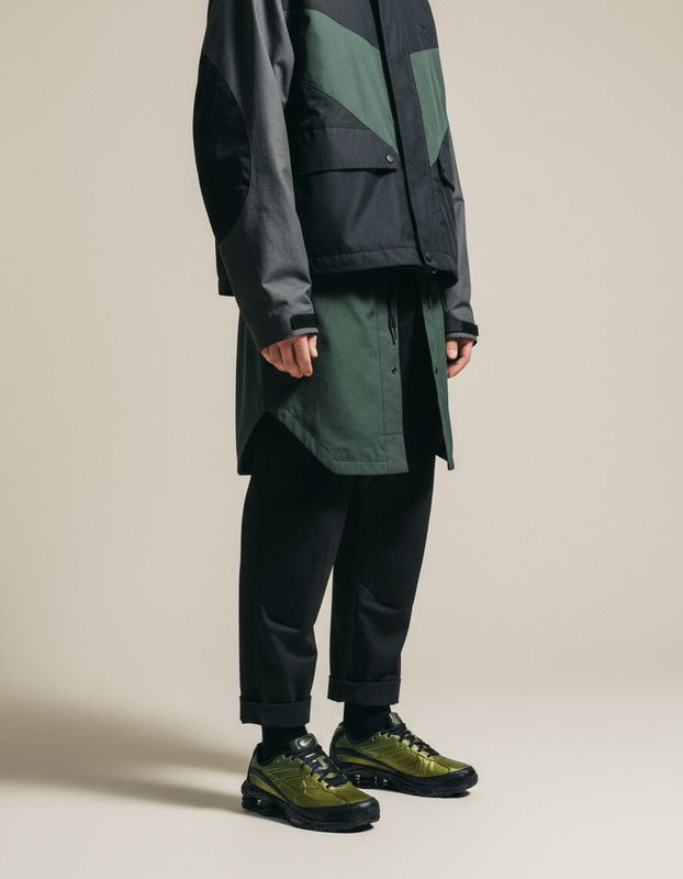 a man in a black jacket and green shoes