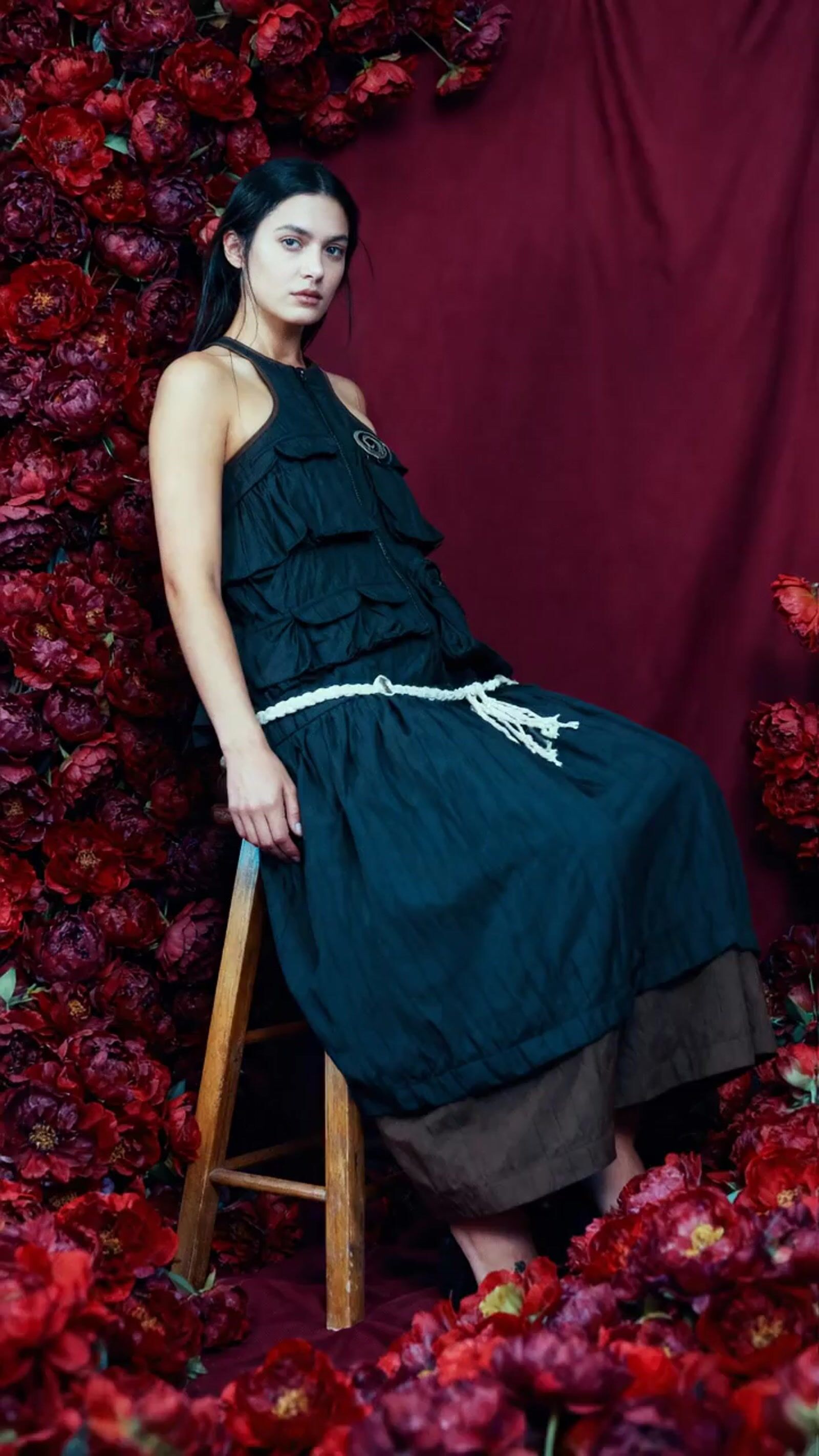 a woman in a black dress sitting on a chair