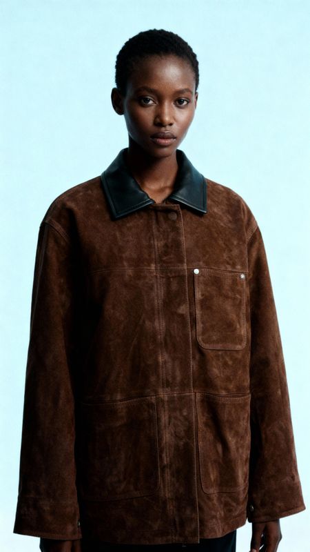 a woman wearing a brown jacket and black pants