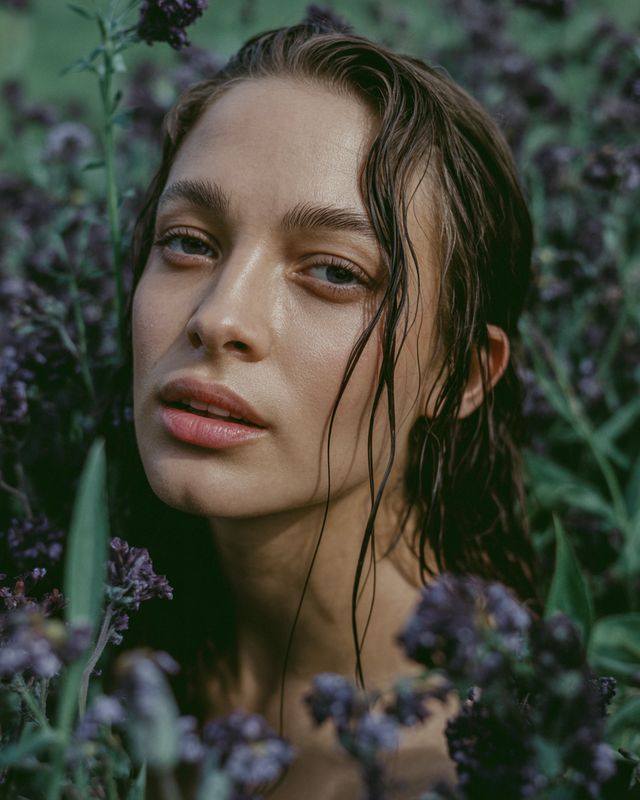 a woman with wet hair standing in a field of flowers