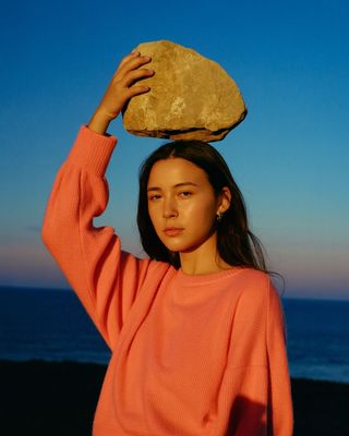 a woman is holding a rock on her head