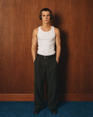 a man wearing headphones standing in front of a wooden wall
