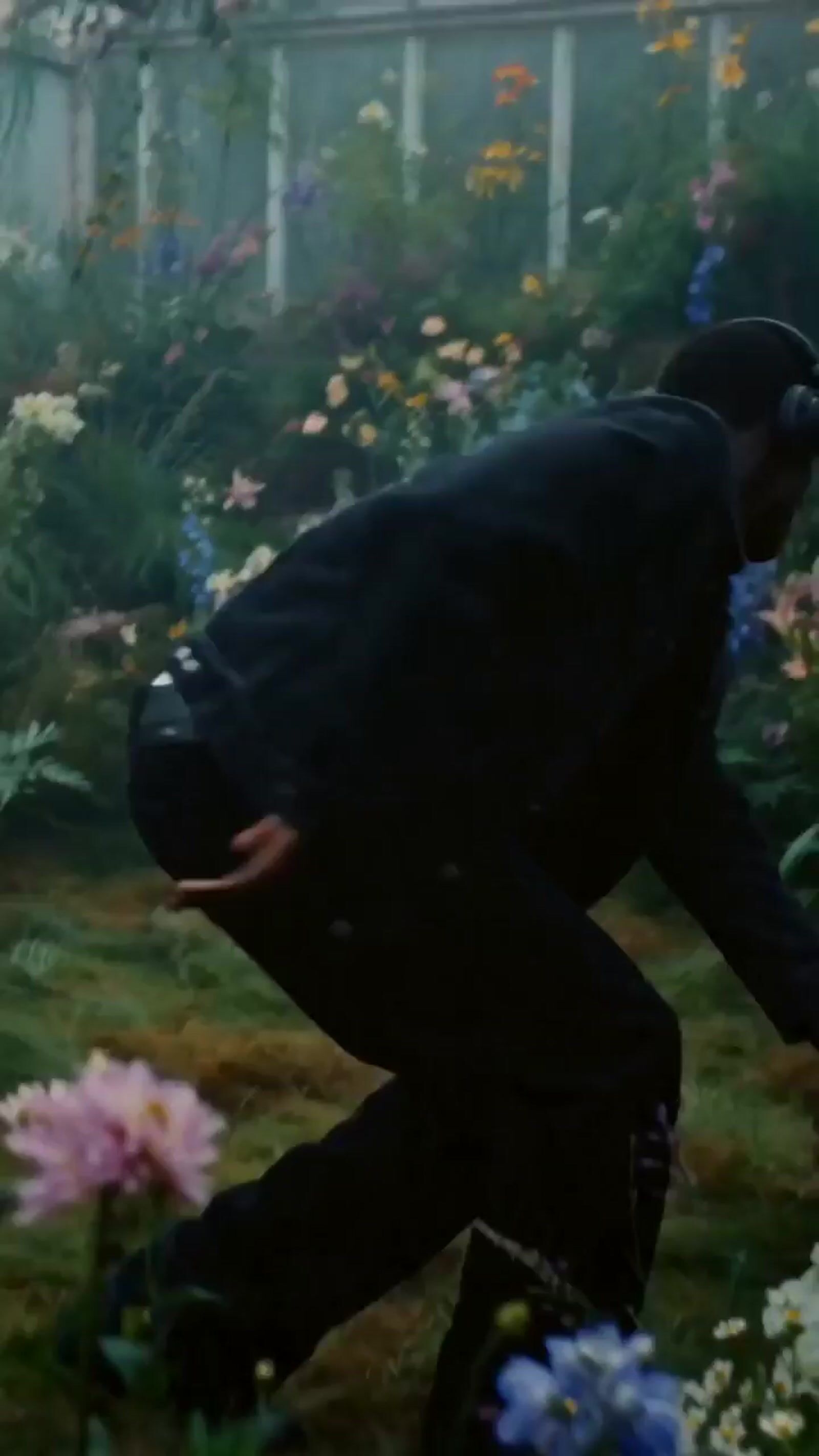 a man in a black suit and hat in a garden