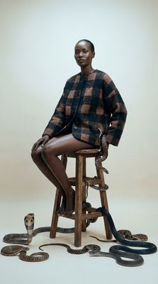a woman sitting on a stool with snakes around her