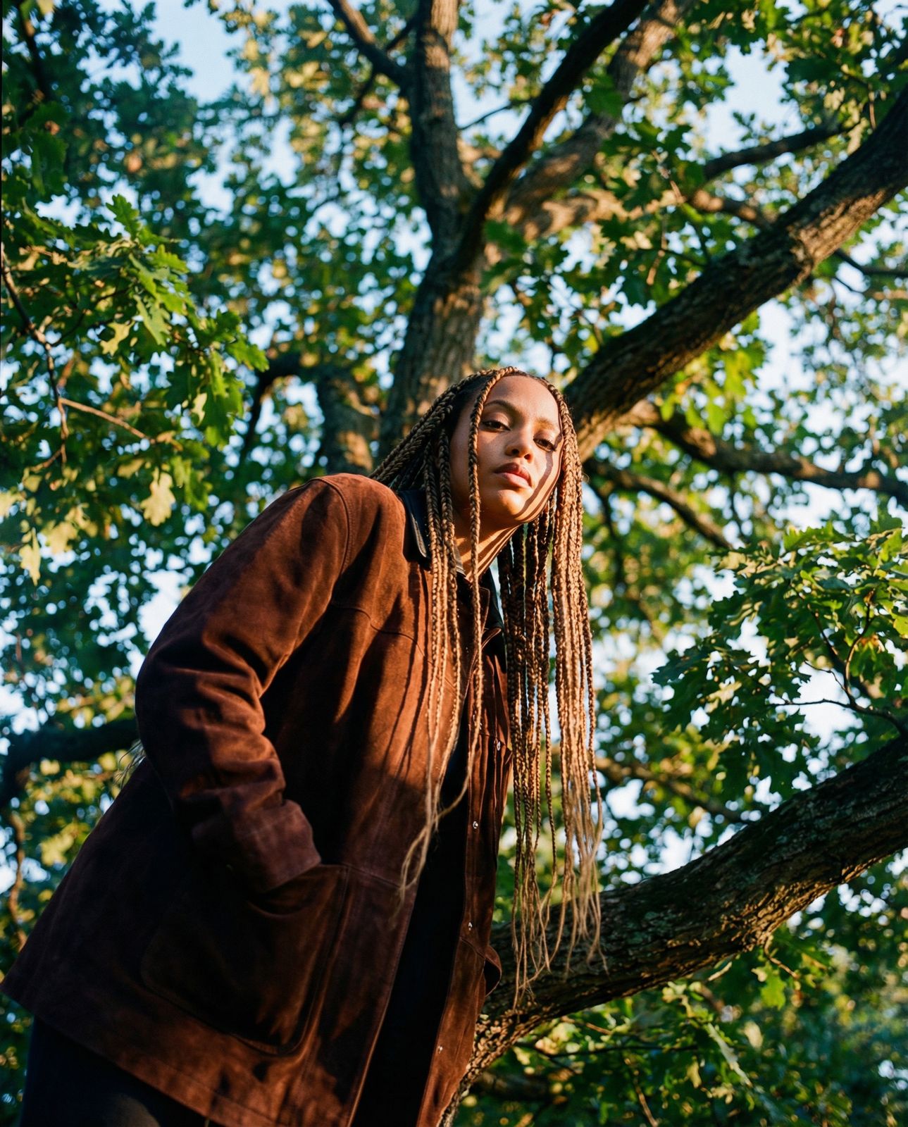 a woman with dreadlocks standing in front of a tree