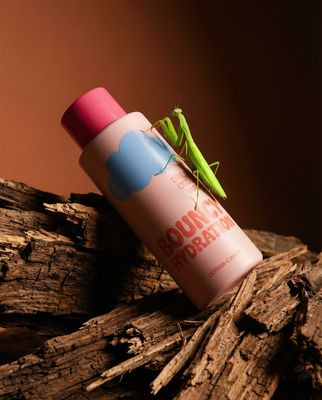 a green insect sitting on top of a pink tube