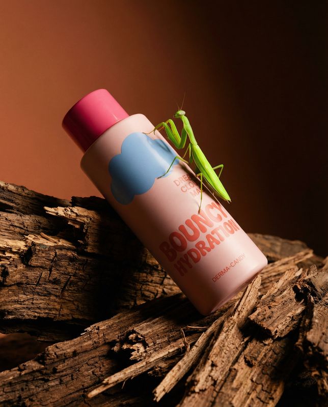 a green insect sitting on top of a pink tube