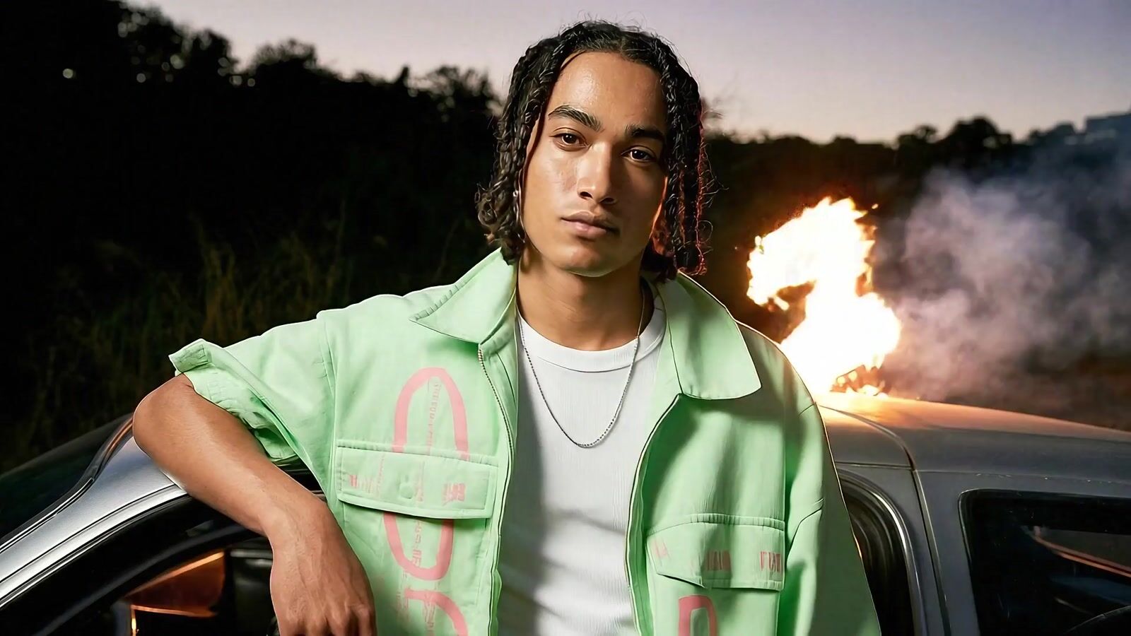 a man with dreadlocks leaning on a car