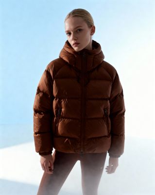 a woman in a brown jacket standing in the snow