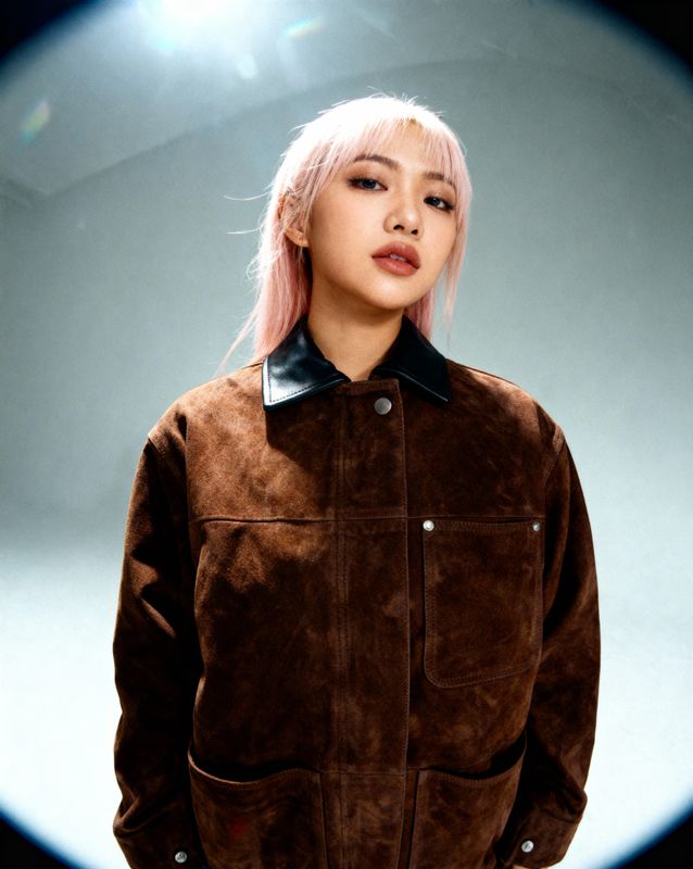 a woman with pink hair wearing a brown jacket