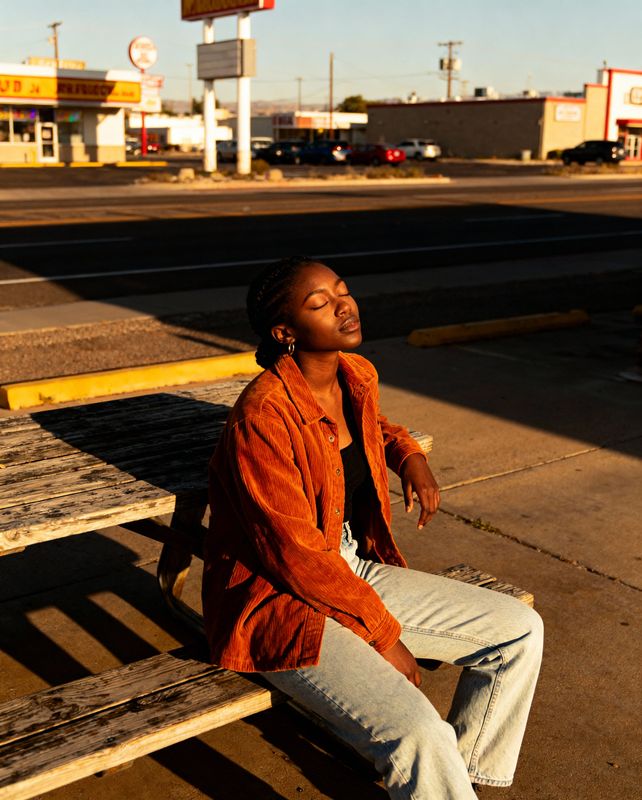 a woman sitting on a bench in front of a gas station