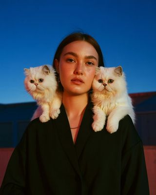 a woman with two cats on her shoulders