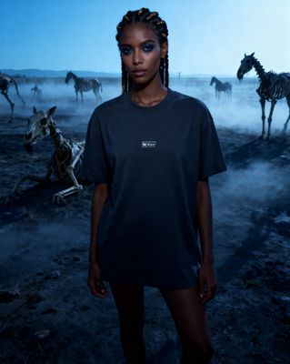 a woman standing in front of a herd of zebras