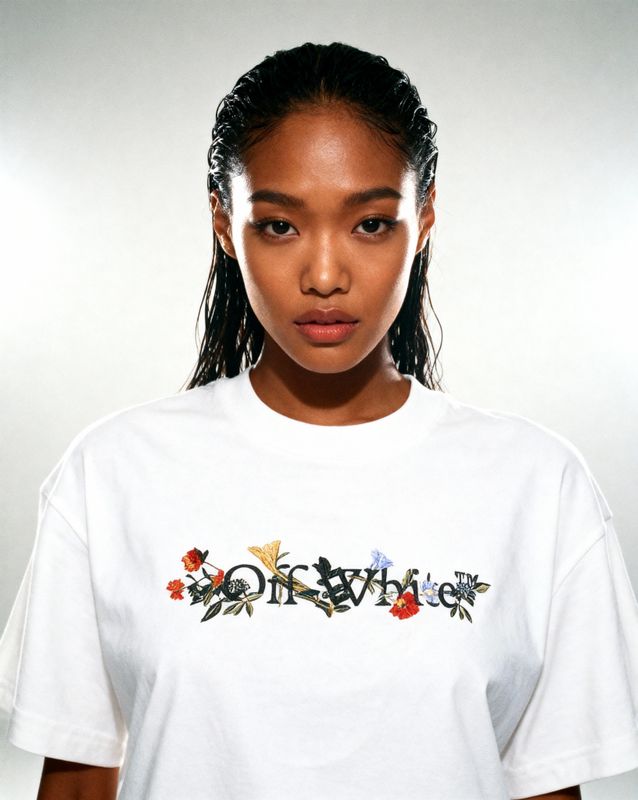 a woman wearing a white t - shirt with flowers on it