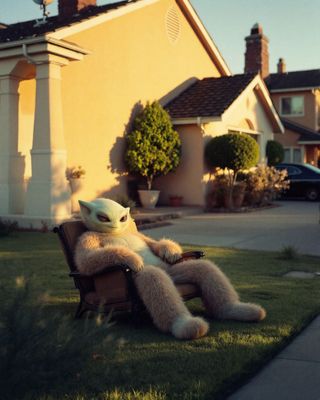 a teddy bear sitting on a lawn chair in front of a house