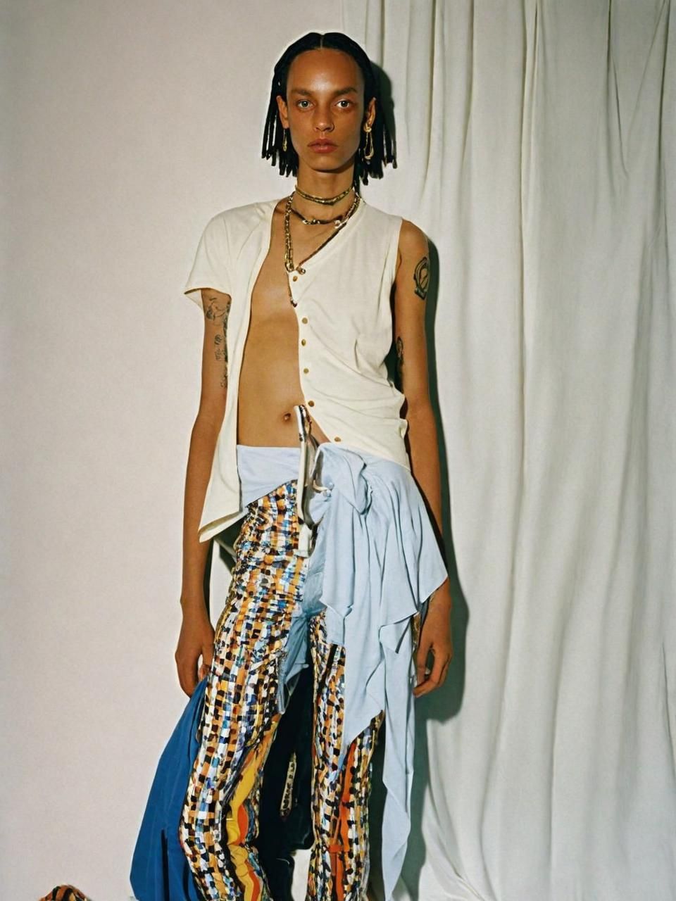 a man with dreadlocks standing in front of a white backdrop