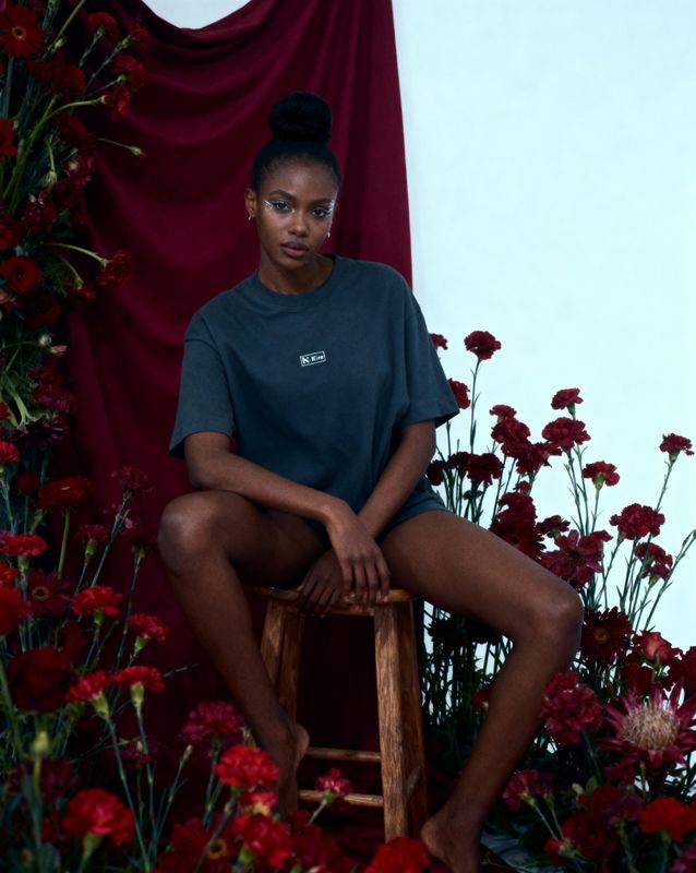 a woman sitting on a stool in front of flowers