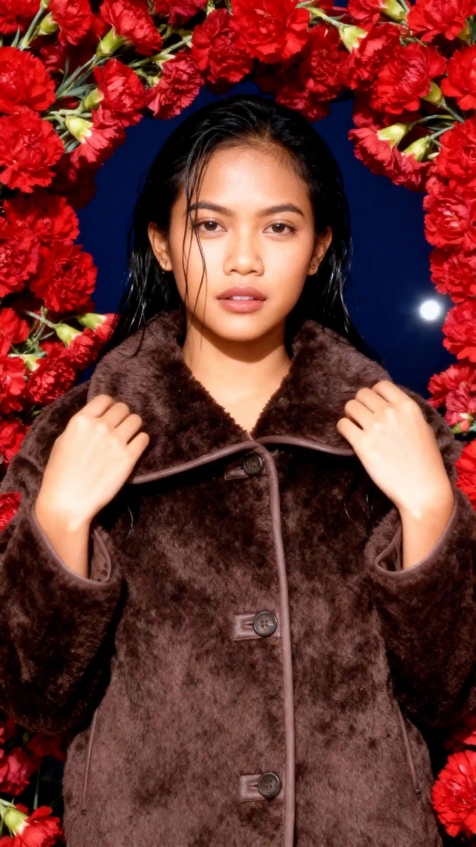 a woman standing in front of a wreath of flowers
