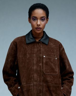 a woman wearing a brown jacket with a black collar