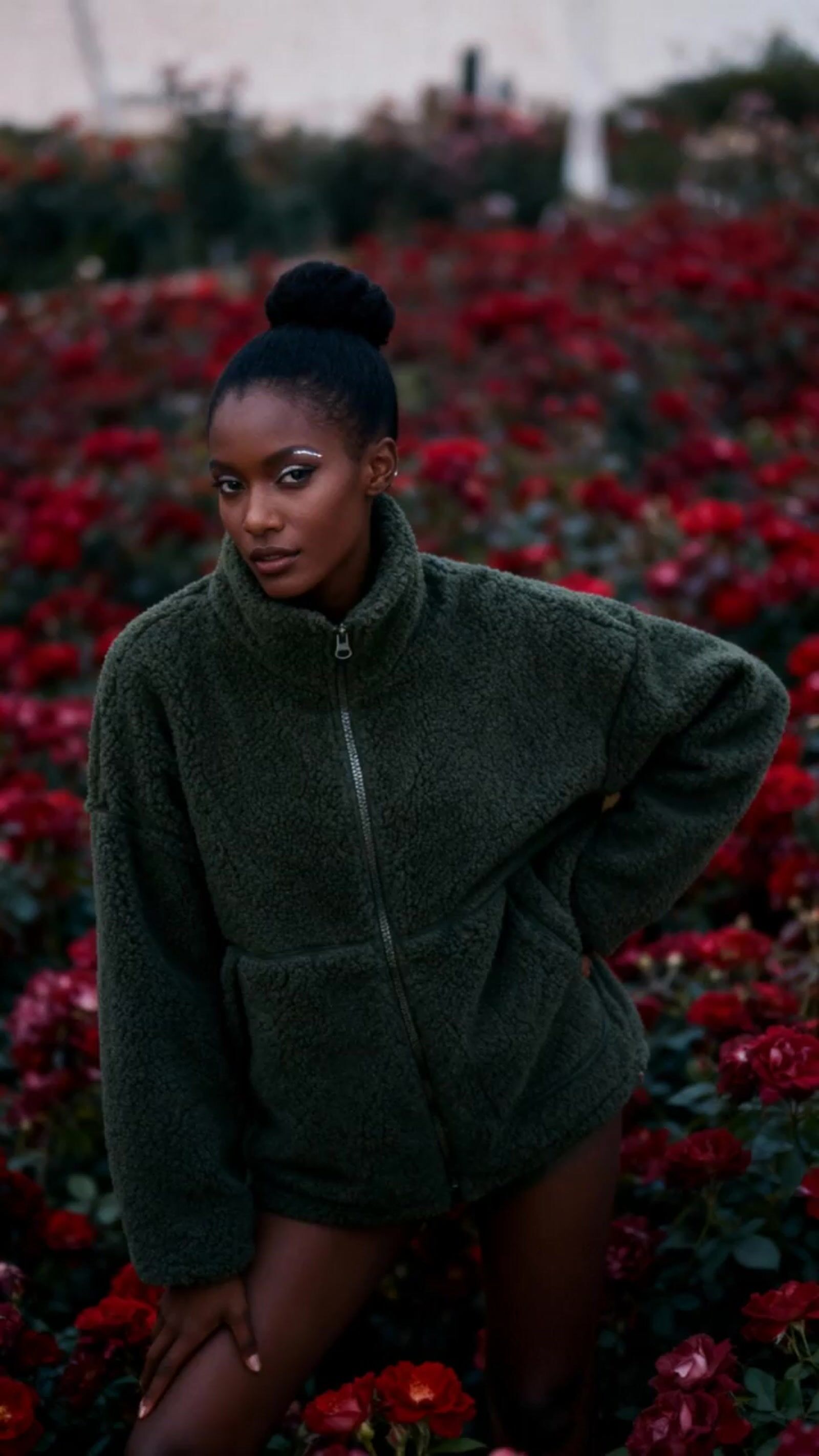 a woman standing in a field of red flowers