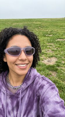 a woman wearing sunglasses sitting in a field