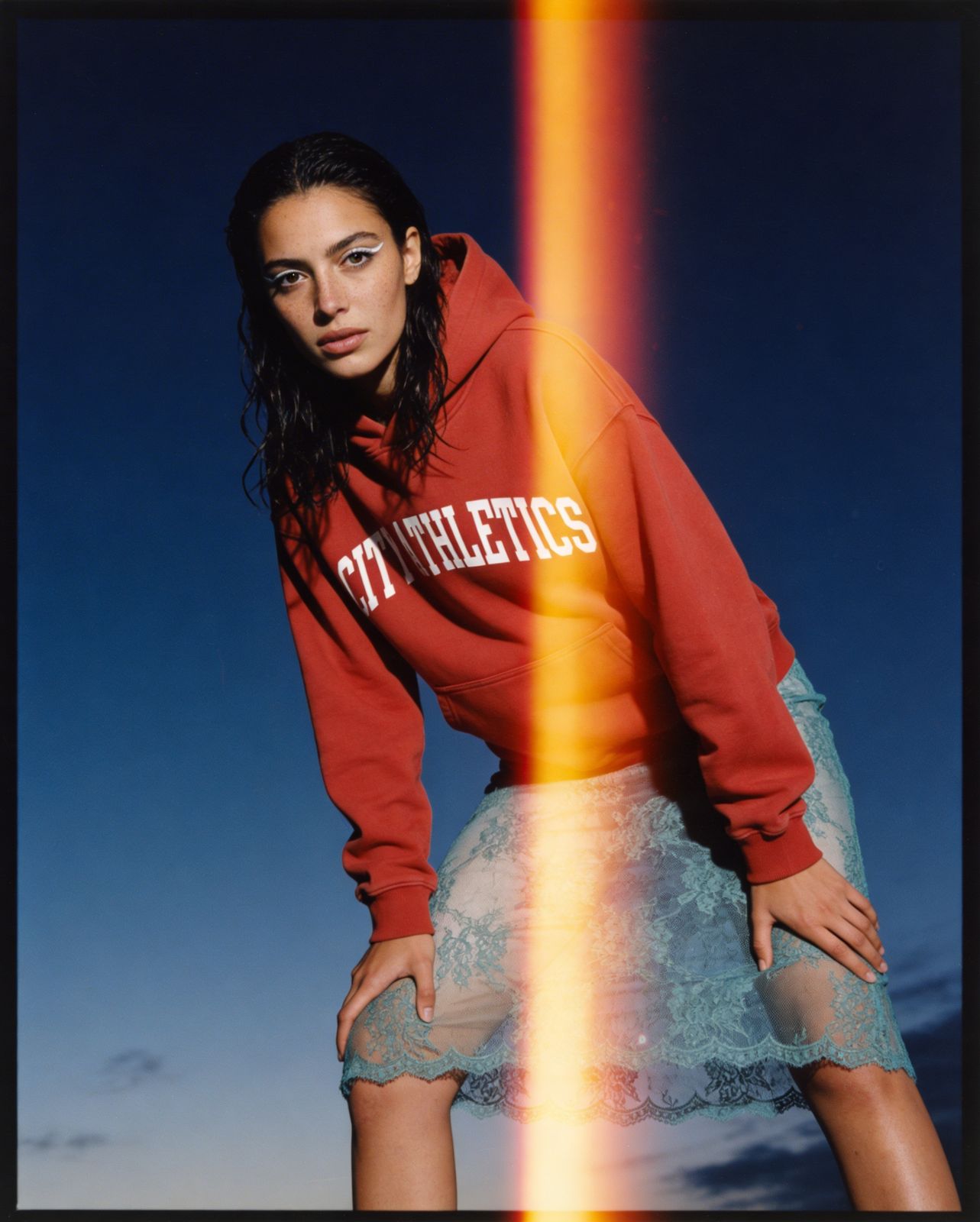 a woman wearing a red sweatshirt and a skirt
