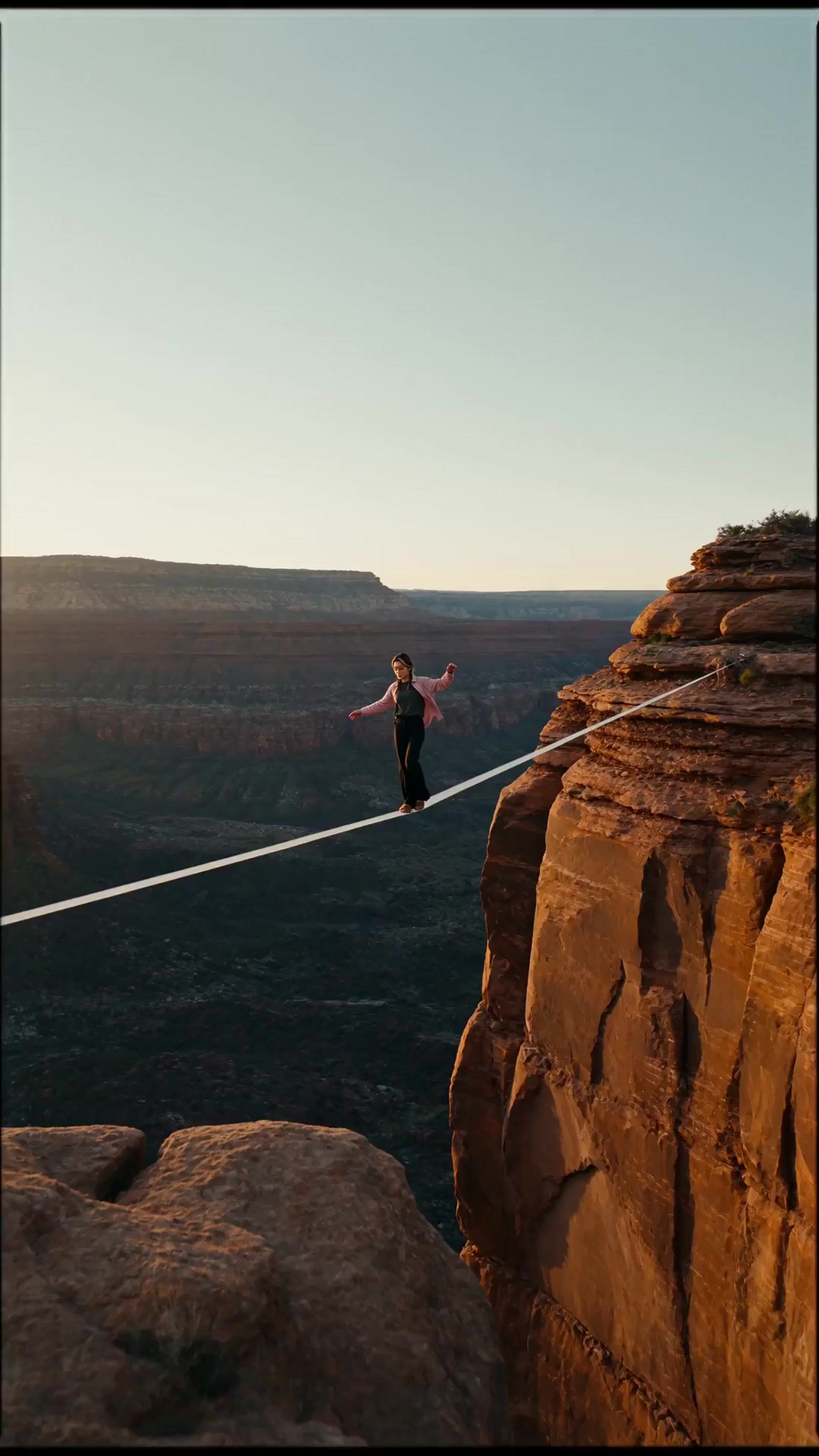 a man walking across a rope over a canyon