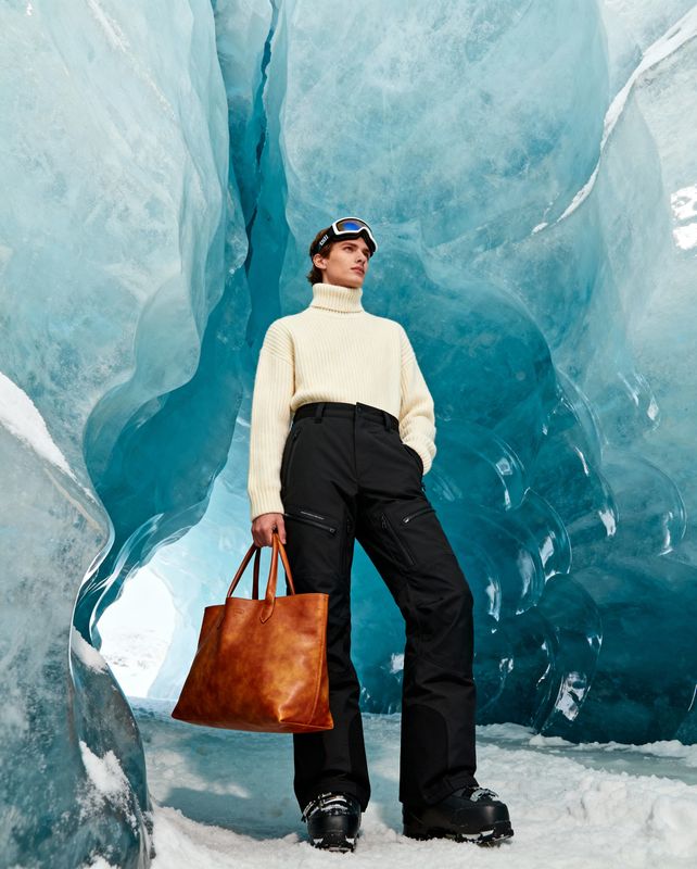 a woman holding a brown bag standing in front of an ice cave