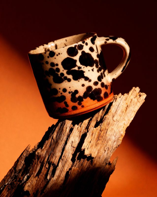 a coffee cup sitting on top of a piece of wood