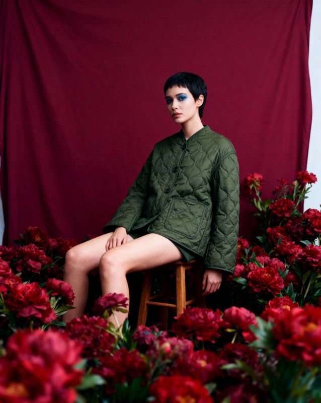 a woman sitting in a chair surrounded by flowers