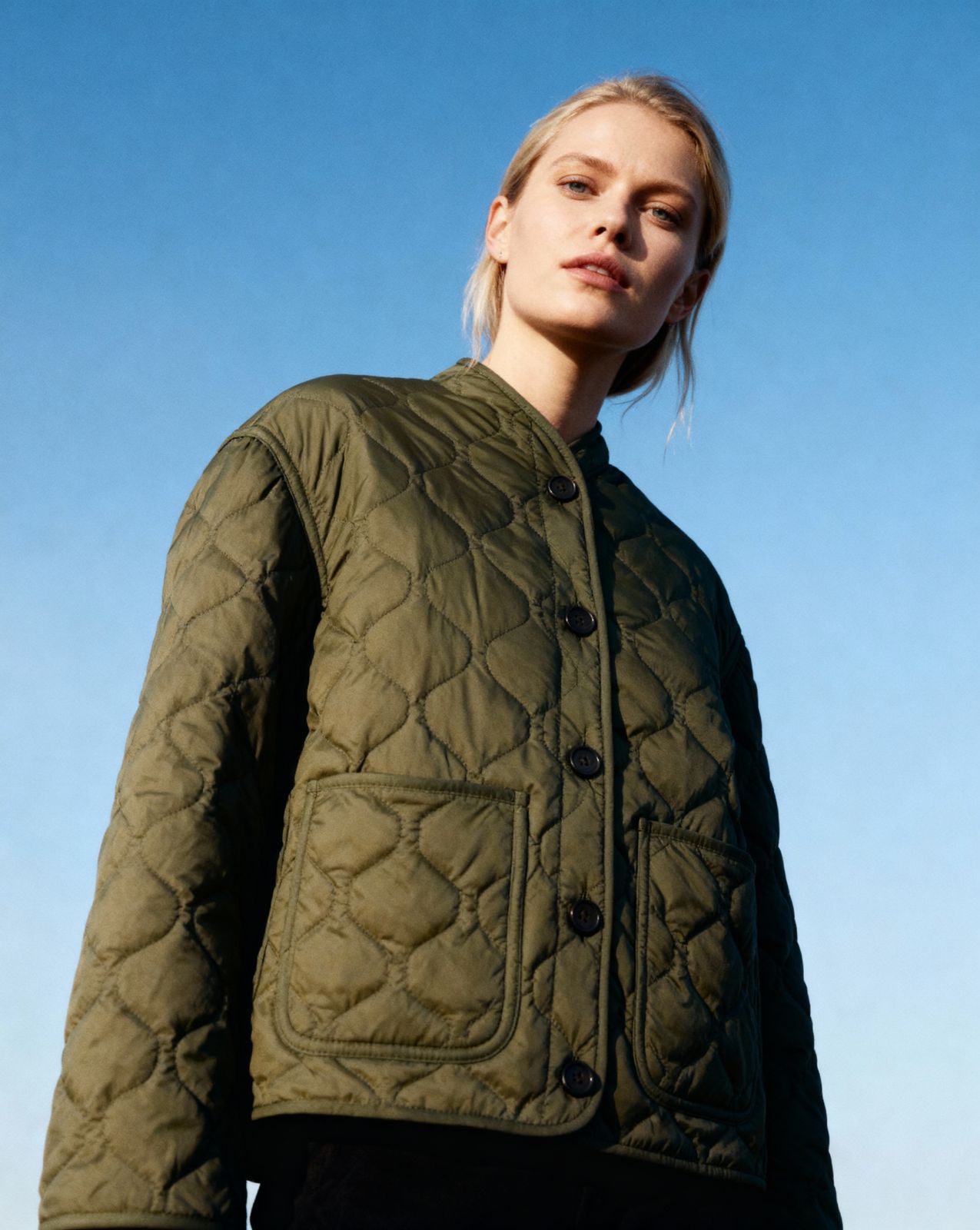 a woman wearing a green jacket and black pants
