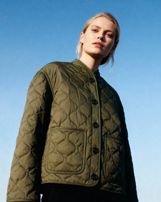 a woman wearing a green jacket and black pants