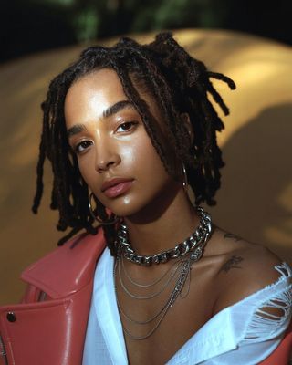 a woman with dreadlocks and a pink jacket