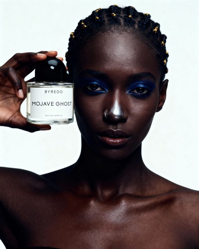 a woman holding a bottle of makeup in front of her face