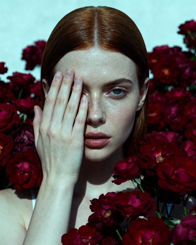 a woman with red hair holding her hand to her face